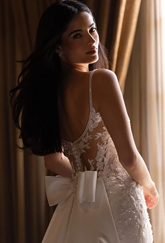 Bride wearing wedding gown with bow back detail, lace and spaghetti straps