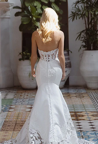 Bride wearing strapless fit and flare wedding dress with lace details and fabric covered buttons