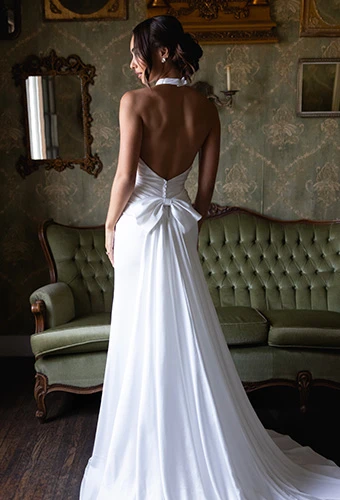 Bride wearing simple halter neck wedding gown with bow back detail