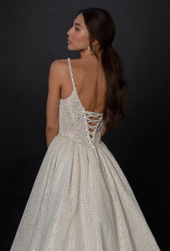 Bride wearing sparkling ballgown wedding dress with spaghetti straps and lace up back