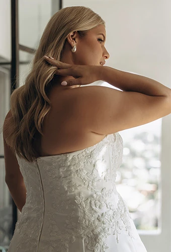 Plus size bride wearing strapless wedding dress with lace