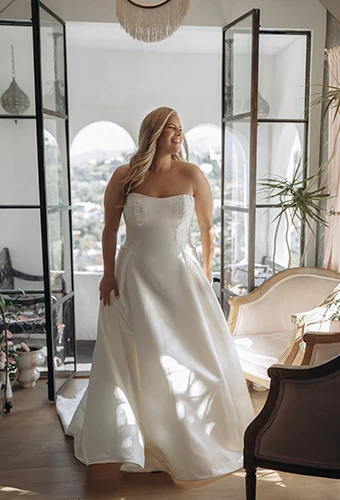 Plus-size bride wearing strapless satin wedding dress with floral lace detailing, Stella York SY8279+