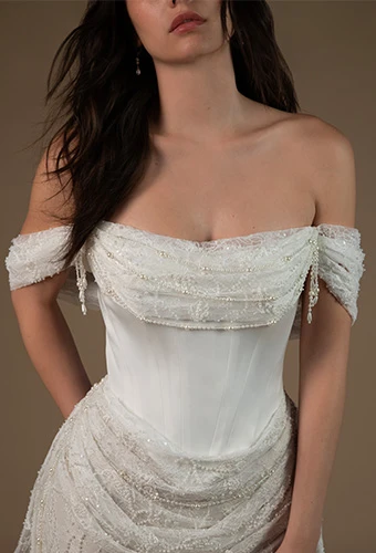 Bride wearing lace wedding dress with pearl detailing and off the shoulder straps